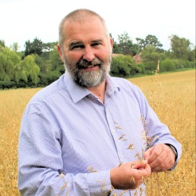 John Cussans standing in a field of oats 