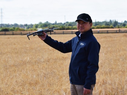 Professor Ji Zhou holding a drone in an arable field