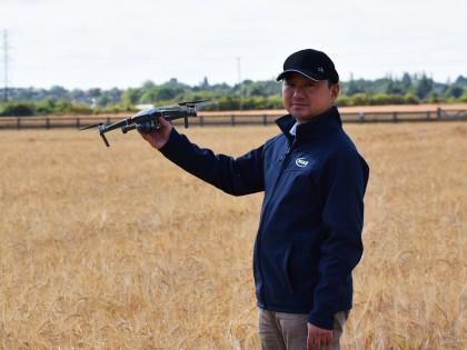 Professor Ji Zhou holding a drone in an arable field
